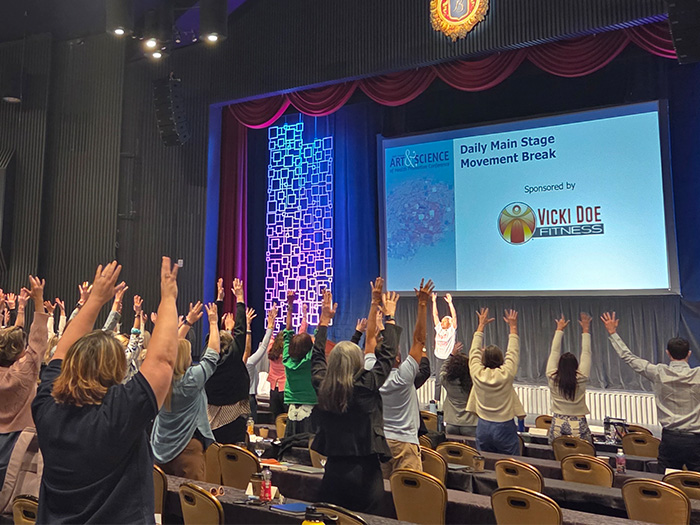 An audience participating in an event prompted by a screen with a sponsor on it