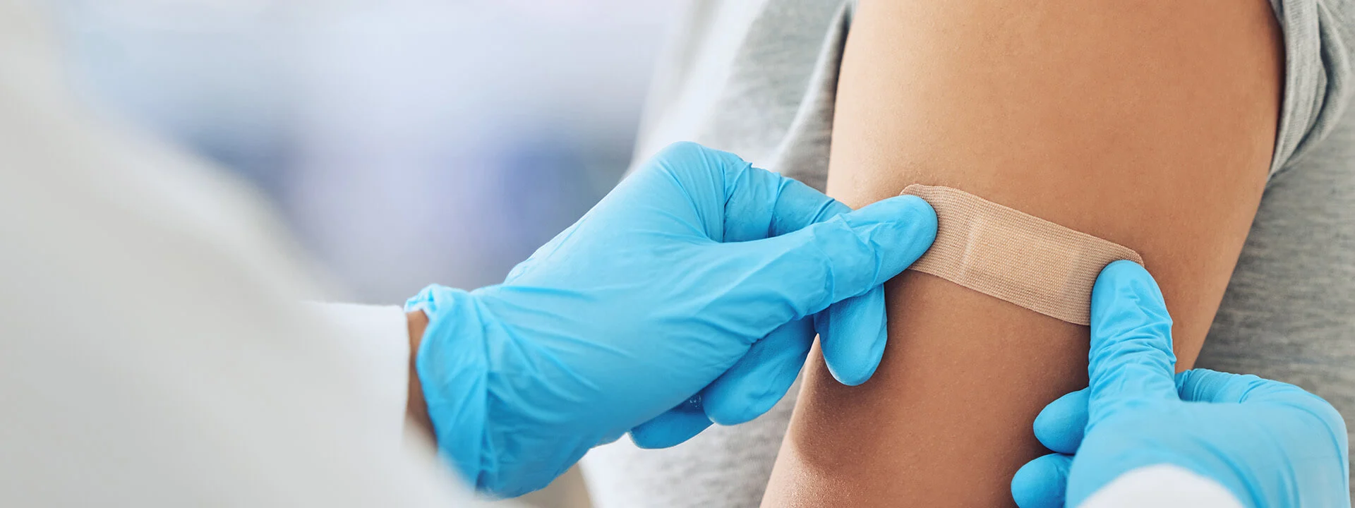 Close up of someone putting a Band-Aid on someone else's arm