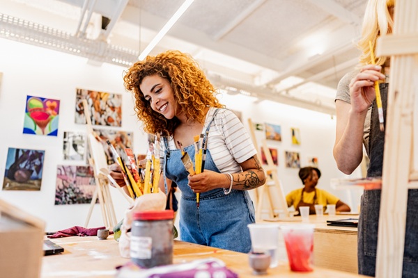 Mid adult woman picking paintbrushes in an art class