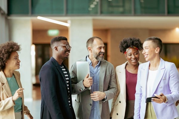Group of Diverse Coworkers Standing at the Office Corridor and Smiling while Having an Informal Conversation