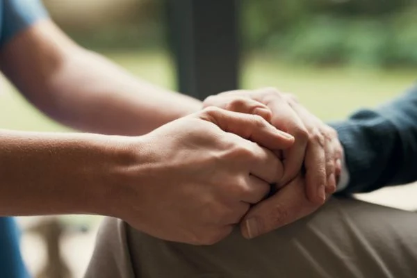 Closeup, hands and support with hope, empathy and praying with trust, healing together and grief. Zoom, elderly woman and person touching palms, compassion or sympathy with bonding, comfort and loss