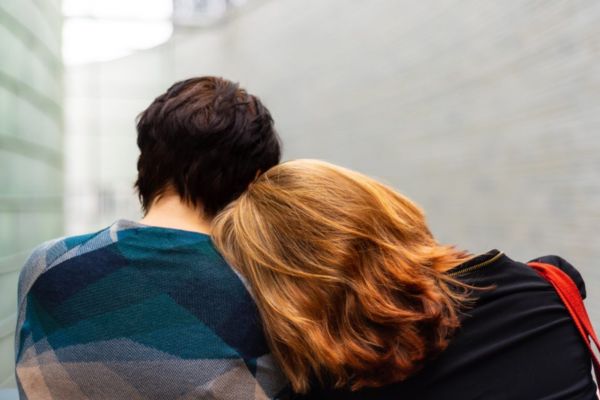 Two people lean on each other for emotional support.
