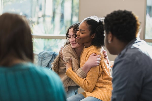 Colleagues hugging each other, offering support and connection.
