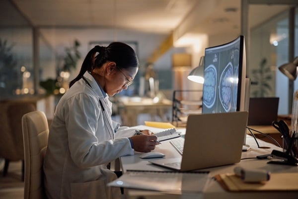 Woman conducting neuroscience research in a lab, looking at brain scans.