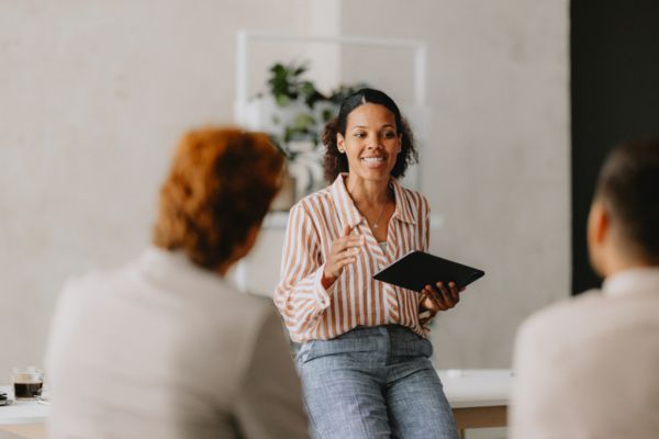 onfident businesswoman leading a group business meeting at a bright beige office. Professional interaction and teamwork concept.