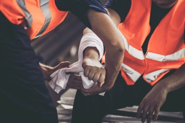 Close up of manual worker assisting his colleague with physical injury in steel mill.