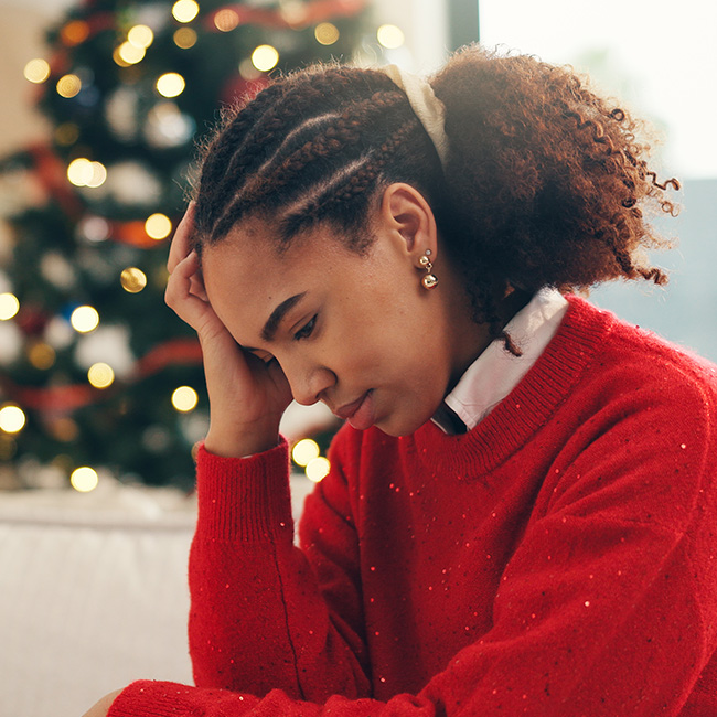 A woman holding her head, with Christmas tree in background