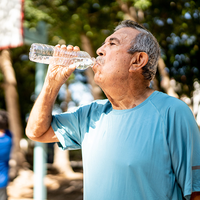 An older man drinking a bottle of water