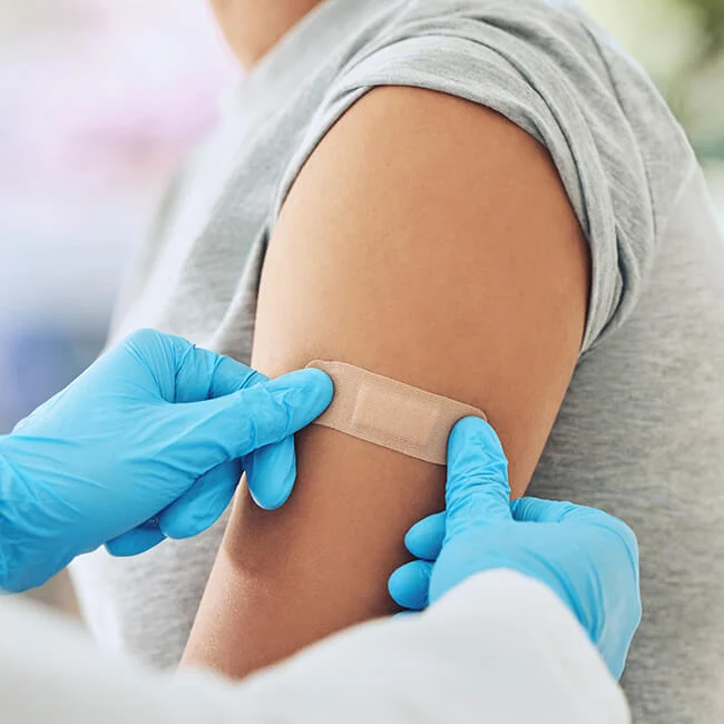 Close up of someone putting a Band-Aid on someone else's arm