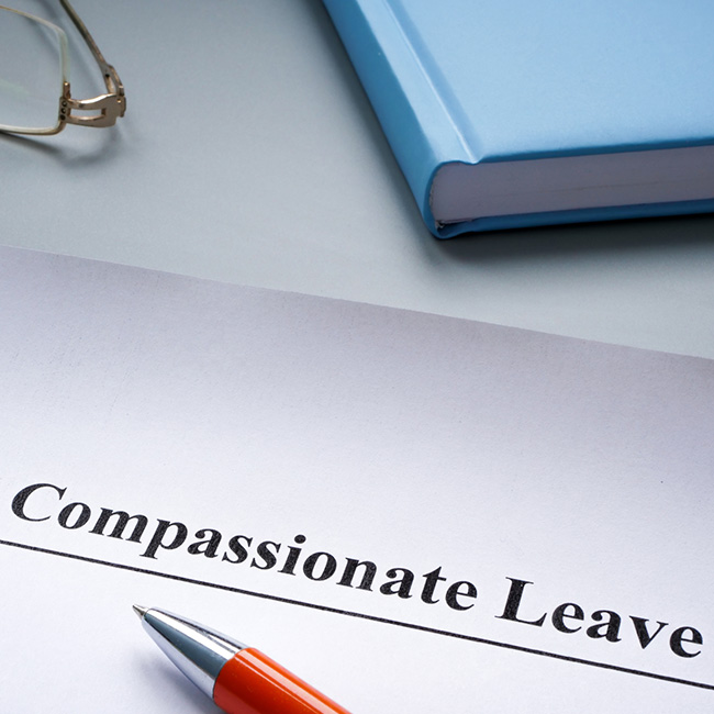 Desk items including a paper with a Compassionate Leave heading