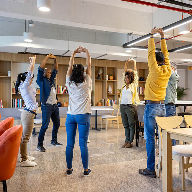 People standing in a circle with arms raised, stretching