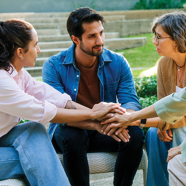 A group of people consoling someone, stacking their hands together