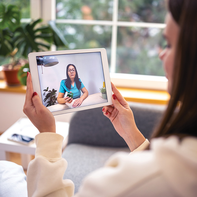 Woman holding a tablet with a health professional on the screen