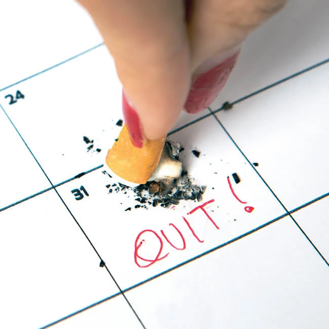 Someone extinguishing a cigarette on a calendar day marked QUIT!